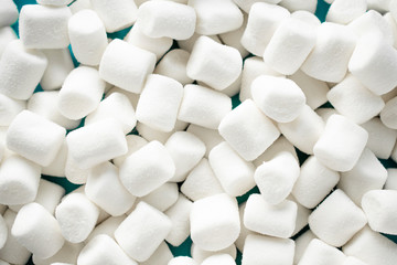 Many small white marshmallows are scattered on the table
