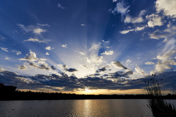 Beautiful sunset on the lake.Blue sky after rain with sunbeams through the clouds.