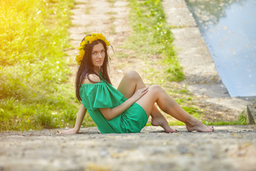 beautiful girl enjoys spring with a wreath of dandelions on her head