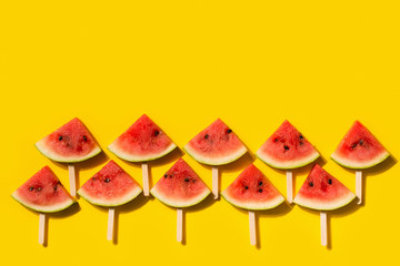 Watermelon slices with stick flat lay on yellow background