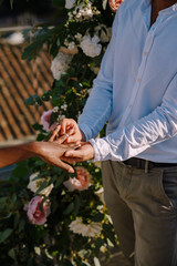 Interracial wedding couple - African-American bride and Caucasian groom. Groom puts a ring on brides finger. Destination fine-art wedding in Florence, Italy. Wedding ceremony on the roof
