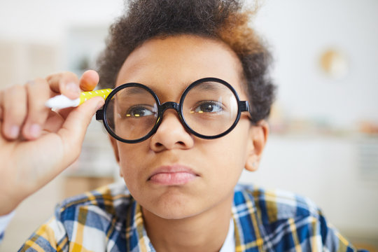 Close Up Portrait Of Cute African-American Boy Wearing Big Glasses Frowning And Pouting While Doing Homework