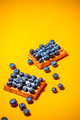 Sweet Homemade waffles with fresh raspberries, blueberries and cream on wooden table background