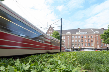 Obraz premium A moving tram at day, houses in background, blue sky, in long exposure. The Hague, the Netherlands