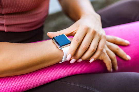 Closeup female holding pink yoga mat and checking pulse on smartwatch after sport trainings, looking at wristwatch black empty display, technology device with calories count app, weight loss program