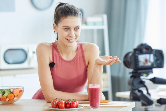 Portrait of fit young woman talking to camera while recording cooking video for sport blog, copy space