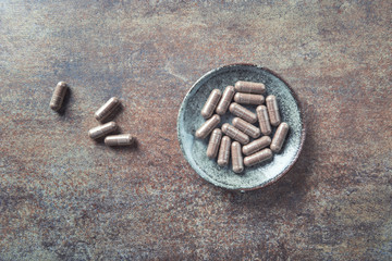 Schisandra chinensis. Herbal capsules with healthy medical plant. Healthy supplement on rustic stone background. Top view. Copy space.	