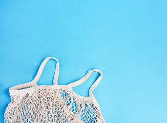 Cotton net bag on a blue background. Sustainable lifestyle. Eco friendly concept. Top view