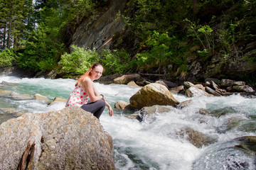 Young woman sits on a stone near the river