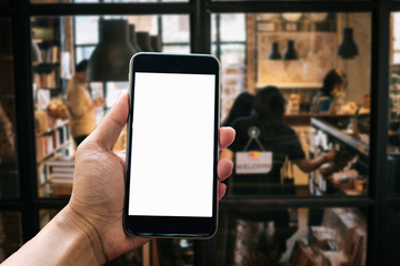 A woman hand holding smart phone device in the coffee shop or cafe background.
