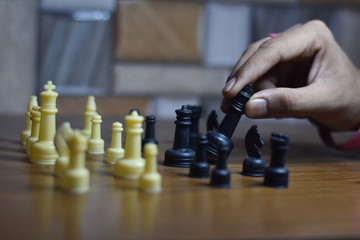 two people playing chess on wooden table, with shallow depth of filed, life during lock down India