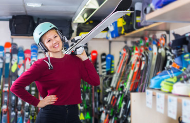 Woman in helmet is demonstraiting ski in shop.