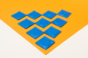 packs with condoms on orange surface isolated on white