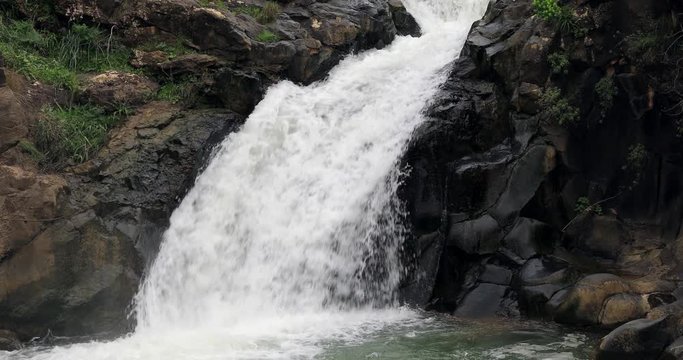 High waterfall and greenery all around.