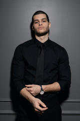 Young handsome businessman in black shirt. Confident young businessman posing on gray background