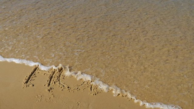 inscription in the sand. The sea wave washes away the word hope. Slow motion.