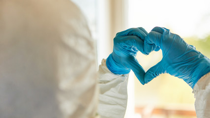 Klinikpersonal hält Herz mit Händen vor Fenster als Coronavirus Unterstützung