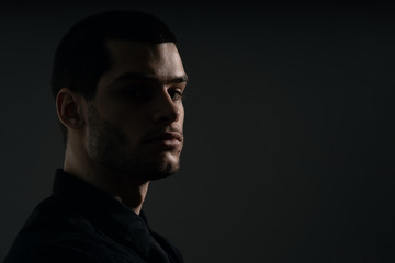 Obraz premium Low-key portrait of modern business person. Handsome businessman standing on dark background
