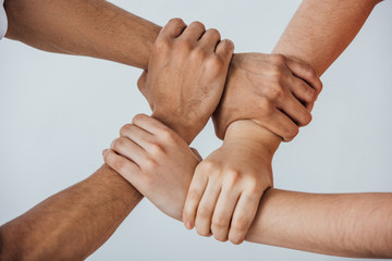 Cropped view of multiethnic men doing unity gesture isolated on grey