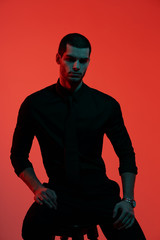 Obraz premium Portrait of a young confident handsome businessman in blue and red light. Studio shot on red background with copy space