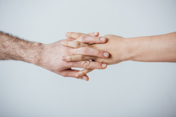 Cropped view of man and woman holding hands isolated on grey