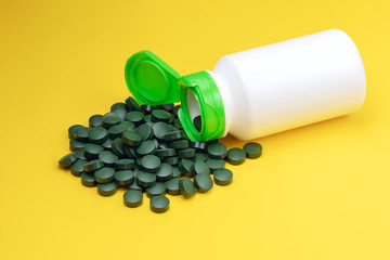 Close-up spirulina algae tablets. Chlorella tablets isolated on yellow background. Diet and nutrition, superfood vegan organic healthy lifestyle concept.