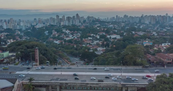 Aerial hyperlapse with intense traffic during the day in city full of trees. Sumare avenue and Pacaembu neighborhood with Sao Paulo skyline in the background