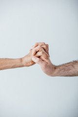 Cropped view of men holding hands isolated on grey