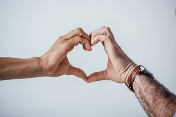 Cropped view of men showing love sign with hands isolated on grey