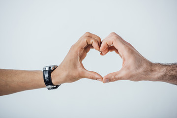 Cropped view of men hands showing heart sign isolated on grey