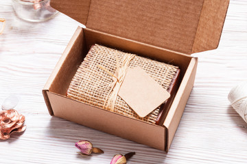 Bar of homemade soap wrapped in hemp fabric on wood background