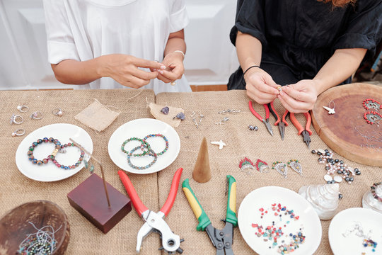 Women using various tools when making beautiful jewelry like earrings and bracelets with natural stones