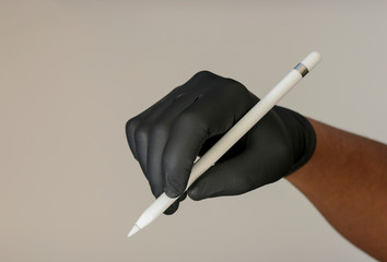 Hand with black glove holding electronic wireless tablet stylus pencil pen. 