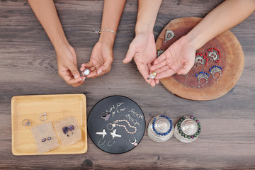 Hands of women checking beautiful earrings they made in workshop with natural stone beads