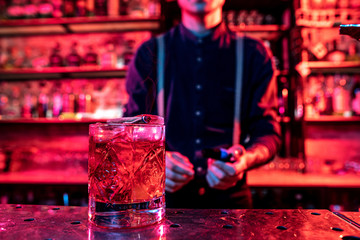 Close up of alcoholic cocktail, beverage, drink, prepared by professional barman in multicolored neon light. Entertainment, drinks, service concept. Modern bar, trendy neoned colors, copyspace.
