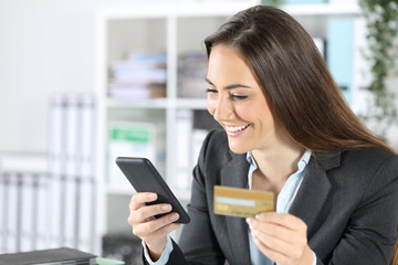 Fototapeta premium Happy executive paying with card on phone at office
