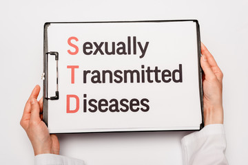 cropped view of doctor holding clipboard with sexually transmitted diseases lettering isolated on...