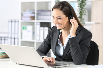 Happy telemarketer with laptop attending call at office - obrazy, fototapety, plakaty