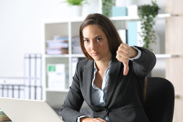 Serious executive gesturing thumbs down at office