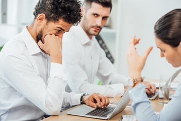 Selective focus of african american businessman using laptop near multiethnic colleagues in office