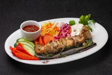 Meat skewers on a plate with vegetables, traditional meat food on fire