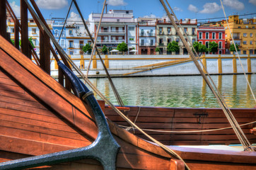 Anchor of the replica of Nao Victoria ship in Seville, Andalusia, Spain (selective focus) with the Triana neighborhood in the background.