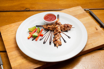 Meat skewers on a plate with vegetables, traditional meat food on fire