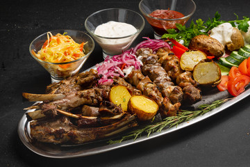Meat skewers on a plate with vegetables, traditional meat food on fire