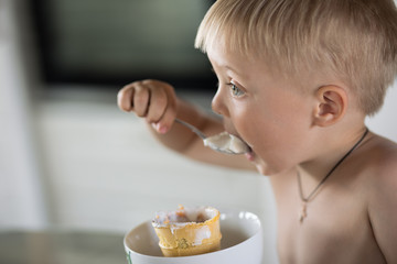 Little boy eats a spoon of ice cream
