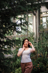 A beautiful young girl walks through an old greenhouse. Woman in the Botanical garden