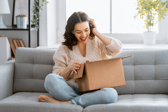 woman is holding cardboard box sitting on sofa at home