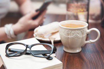 Cup of tea and eyeglasses on book on the table. Cozy home concept