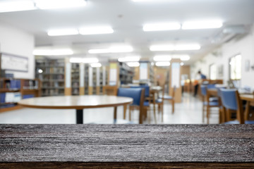 Empty wooden desk space platform with library background for product display montage. Education concept.