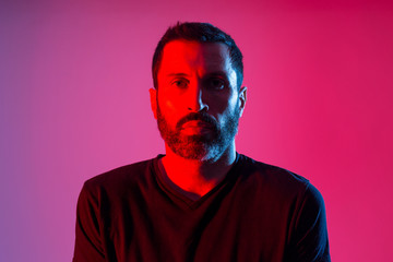 Colorful studio portrait of a bearded man against red and blue background.